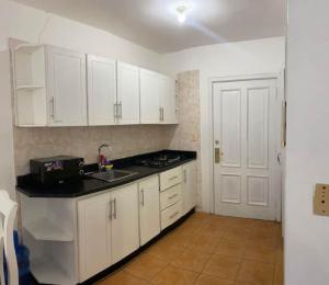 a kitchen with white cabinets and a sink and a door at Appartamento Albatros, Juan Dolio in Juan Dolio