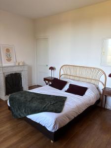 a bedroom with a large bed with white sheets and a fireplace at Maison Mère in Arnac-Pompadour +15 photos