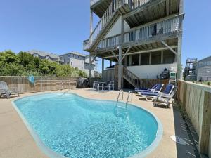 une grande piscine avec des chaises et un bâtiment dans l'établissement SNH263 Gone Coastal, à Nags Head
