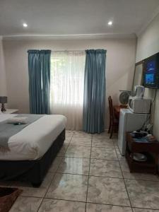 ein Schlafzimmer mit Bett, Schreibtisch und Fenster in der Unterkunft Bunitrix Guesthouse in Summerstrand
