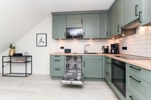 a kitchen with green cabinets and a dishwasher at Hof zwischen den Deichen in Wangerland