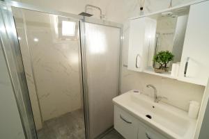a white bathroom with a shower and a sink at Teraslı Müstakil Ev in Cunda +32 photos