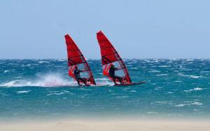 two people windsurfing in the ocean on the water at BADINE BEACH 5 personnes vue jardin avec climatisation in Hyères