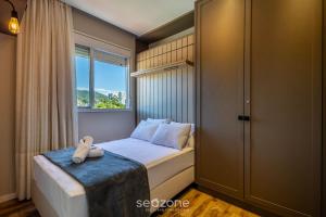 a small bedroom with a bed with a window at Estadia sofisticada a 200m da Praia Brava - EHI in Praia Brava