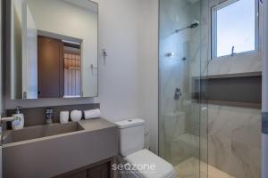 a bathroom with a toilet and a glass shower at Estadia sofisticada a 200m da Praia Brava - EHI in Praia Brava +43 photos