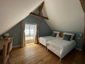 two beds in a attic bedroom with a window at Le Clos de l'Armançon - Maisons de charme au bord de la rivière - Classé 4 étoiles in Tonnerre