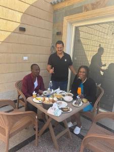 a group of people sitting around a table with food at home in the pyramids in Cairo +13 photos