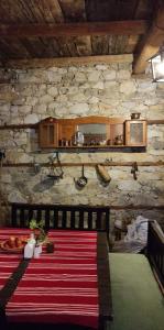 una sala da pranzo con un tavolo e un muro di pietra di Кулинарна къща за гости СОФРИЦА a Hvoyna