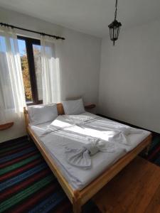 una camera da letto con un letto con lenzuola bianche e una finestra di Кулинарна къща за гости СОФРИЦА a Hvoyna