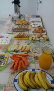 Una mesa cubierta con platos de plátanos y zanahorias en Hotel Pousada Do Viajante, en Erechim