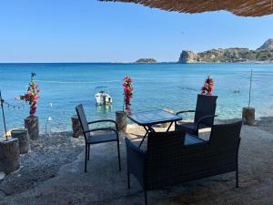 a table and chairs on the beach with a boat in the water at Álas Holiday Home in Archangelos