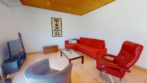 Una sala de estar con un sofá rojo y una mesa. en Le Clos du Cep, en Saint-Hilaire-de-Riez