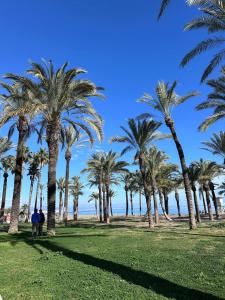 two people walking in a park with palm trees at Sunny apartment Carihuela in Torremolinos