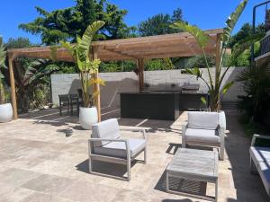 un patio con sedie bianche, tavolo e pergolato in legno di 2 Bed apartment on the Dordogne River a Saint-Seurin-de-Prats