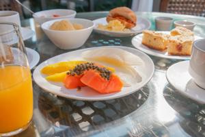 a table topped with plates of food and orange juice at Pousada Dunas da guarda in Guarda do Embaú