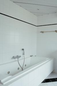 a white bath tub in a white tiled bathroom at Perla di Robbie in Zandvoort +18 photos