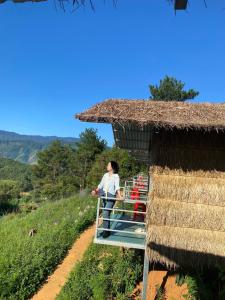 a woman standing outside of a thatch hut at Top view la pán tẩn in Kon Rung (1)