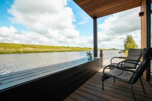 een veranda met 2 stoelen en uitzicht op een rivier bij Garnwerd aan Zee in Garnwerd