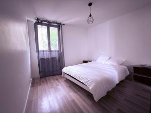 ein weißes Schlafzimmer mit einem Bett und einem Fenster in der Unterkunft Appartement centre historique Auxerre Arrivée autonome in Auxerre