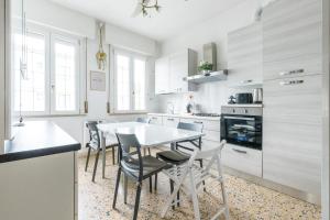 a kitchen with white cabinets and a table and chairs at Marina Dream 200 Meters From The Sea in Marina di Ravenna +27 photos