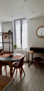 sala de estar con mesa, sillas y piano en Le Saint-Alpin, en Châlons-en-Champagne