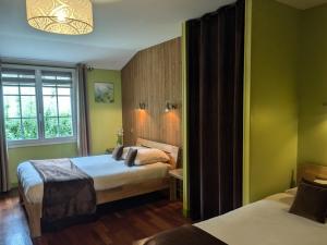 a bedroom with two beds with green walls and a window at Au Saint-Amand in Poissons
