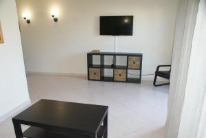 a living room with a black table and a tv at Vila da Praia 7D Alvor in Alvor