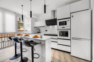 a kitchen with white appliances and a counter with stools at Las Flores Luxury Apartment in Málaga