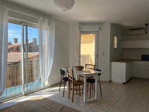 a kitchen with a table and chairs and a large window at Duplex lumineux l 2 ch l balcon l climatisation l Idéal famille l Alpilles in Eyguières