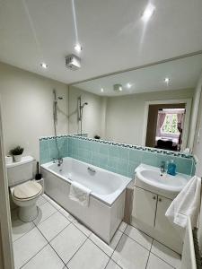 a bathroom with a tub and a toilet and a sink at Woking 2-Bed Flat with Balcony, En-Suite and Parking in Woking