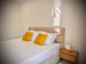 a bed with two yellow pillows and a side table at Dine Hotel in Ksamil