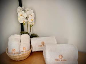 a bunch of towels and a vase with white flowers at Dine Hotel in Ksamil