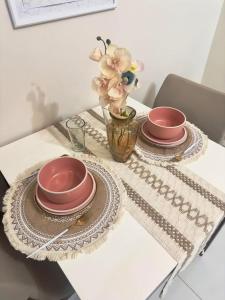 a table with two plates and a vase with flowers at Cozy 1BR Condo with Uptown Mall View - BGC Zen Suite in Manila