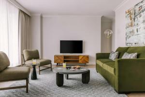 a living room with a green couch and a tv at The Sunset Hotel West End in Vancouver