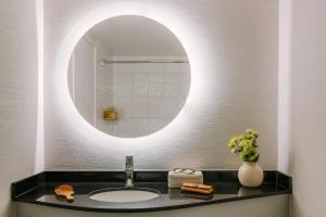 a bathroom with a sink and a round mirror at The Sunset Hotel West End in Vancouver +29 photos
