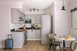 a white kitchen with a refrigerator and a table at The Sunset Hotel West End in Vancouver
