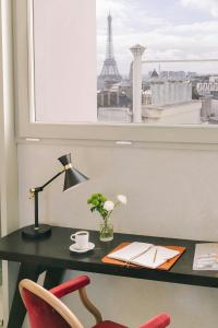 a desk with a lamp and a chair in front of a window at Atala Hotel Champs Elysées, Sonder by Marriott Bonvoy in Paris