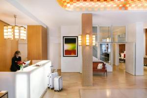 a woman standing in a hotel lobby with her luggage at Atala Hotel Champs Elysées, Sonder by Marriott Bonvoy in Paris
