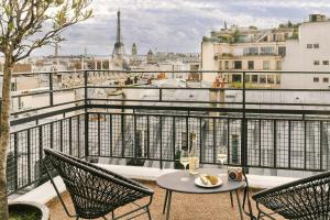 a table and chairs on a balcony with a view of the city at Atala Hotel Champs Elysées, Sonder by Marriott Bonvoy in Paris