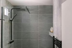 a shower stall in a bathroom with gray tiles at Atala Hotel Champs Elysées, Sonder by Marriott Bonvoy in Paris