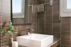 a bathroom with a white sink and black tiles at Atala Hotel Champs Elysées, Sonder by Marriott Bonvoy in Paris