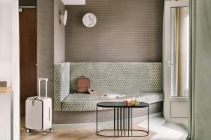 a room with a bench with a table and a clock at Atala Hotel Champs Elysées, Sonder by Marriott Bonvoy in Paris