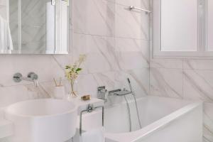 a white bathroom with a sink and a tub at Atala Hotel Champs Elysées, Sonder by Marriott Bonvoy in Paris