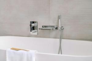 a bathtub with a faucet and a sink in a bathroom at Atala Hotel Champs Elysées, Sonder by Marriott Bonvoy in Paris