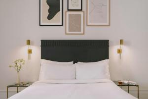 een slaapkamer met een wit bed met ingelijste foto's aan de muur bij Kensington Gardens Hotel, Sonder by Marriott Bonvoy in Londen