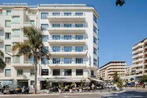 a tall white building with people sitting outside of it at Yelo Promenade Hotel Magnan, Sonder by Marriott Bonvoy in Nice