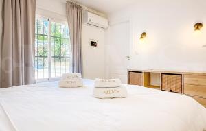 a white bedroom with a large white bed with two pillows at Chic Villa with pool, garden and parking REMS in Fuengirola +42 photos