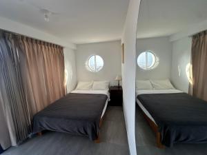 two beds in a room with two windows at Habitación con Terraza Vista al Mar in Pimentel