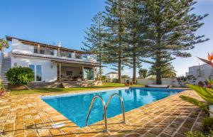 a swimming pool in front of a villa at Exotic Beachfront Retreat Handcrafted Bohemian Luxury in Cádiz