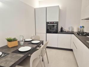 a kitchen with white cabinets and a table and chairs at Piazzetta Signori By Case al Lago in Desenzano del Garda